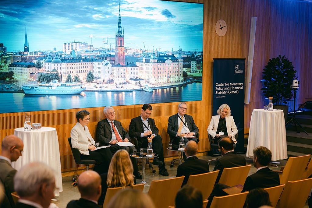 Fem personer sitter i en paneldiskussion inf&ouml;r &aring;h&ouml;rare. Five persons partake in a panel discussion in front of an audience.
